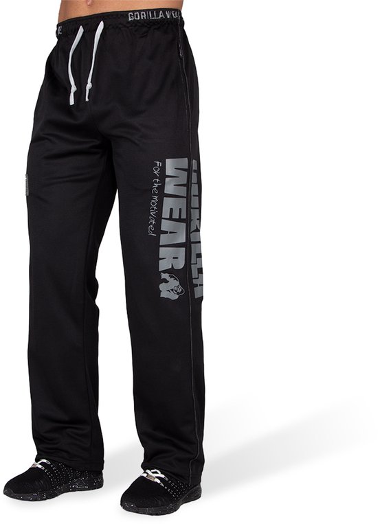 Zwarte trainingsbroek met 'Gorilla Wear' logo en tekst op het linkerbeen, gedragen door een man.