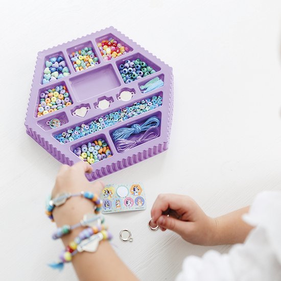Kinderhanden maken armbanden met paarse kralenset, gevuld met veel gekleurde kralen en touw.