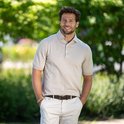 Homme portant un polo beige, un pantalon clair, une ceinture marron et un bracelet de perles.