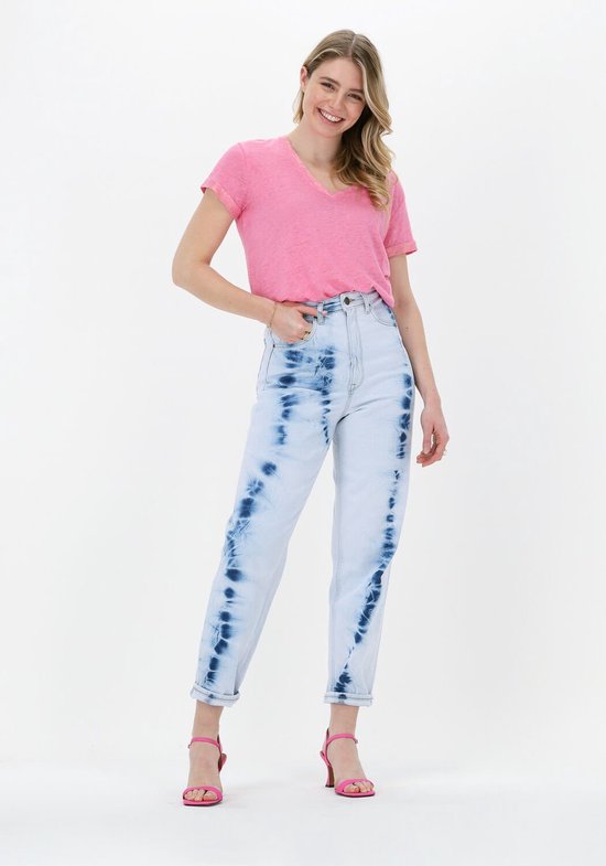 Model in lichtblauwe jeans met blauwe tie-dye print en roze top, staand.