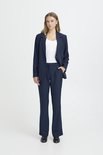 Model draagt een donkerblauwe pantalon met wijde pijpen en bijpassende blazer.
