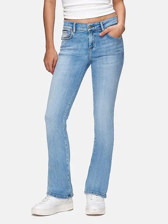 Model draagt een witte tanktop en lichtblauwe flared jeans, staand.