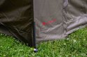 Zijkant van een groene tent met rode 'ULTIMATE' logo en grondpinnen.
