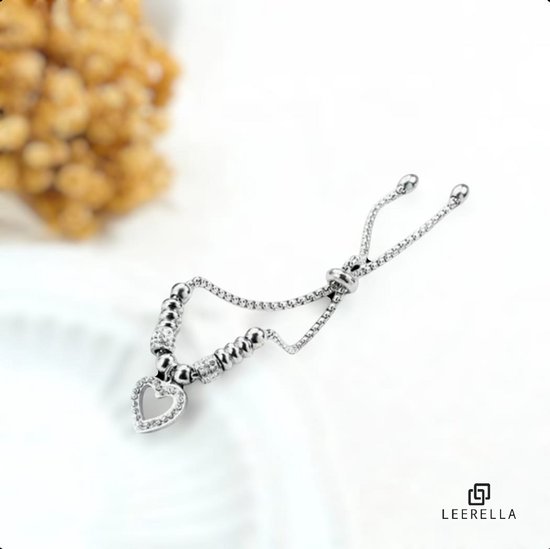 Zilverkleurige verstelbare armband met hartvormige hanger met zirkonia, op een witte ondergrond.