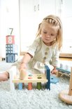 Meisje met blonde vlechtjes slaat met een houten hamer op pinnen.