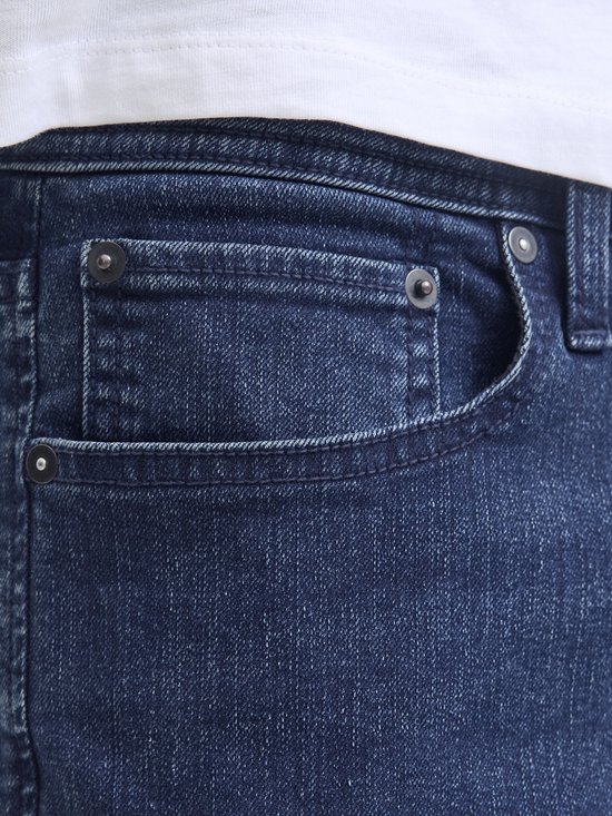 Detail van de donkerblauwe jeans, met de voorzak en klinknagels.