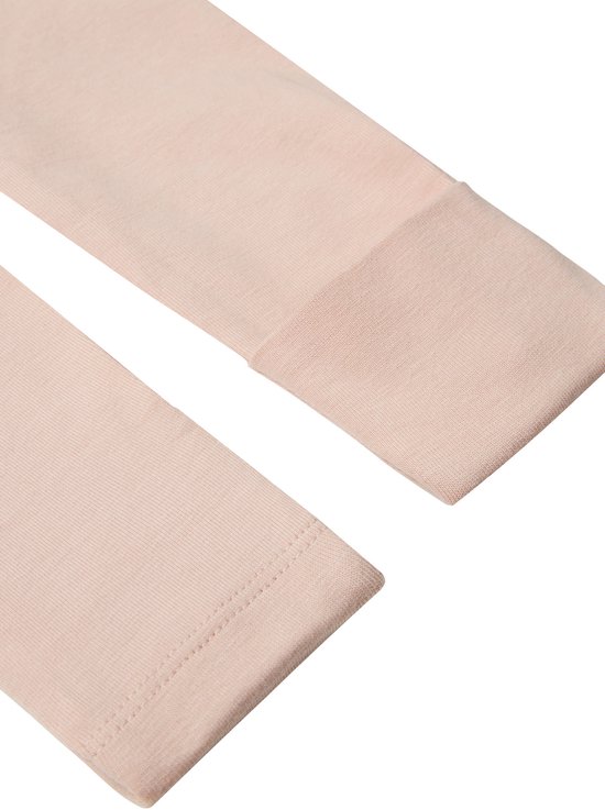 Close-up van de lichtroze stof van een longsleeve shirt met omgeslagen manchetten.