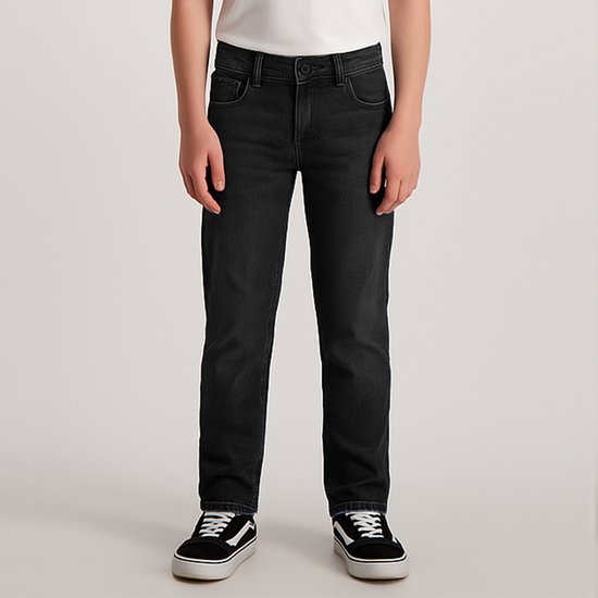Jongen draagt donkergrijze jeans met een witte t-shirt en zwarte sneakers.