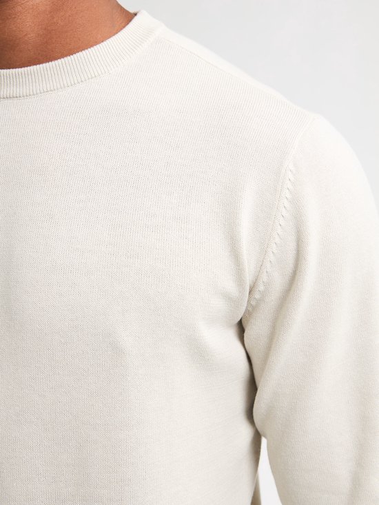 Close-up van de textuur van een beige trui met ronde hals.