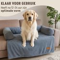 Gouden retriever zit op een grijze hondenbank van ribstof, op een bank. Klaar voor gebruik.