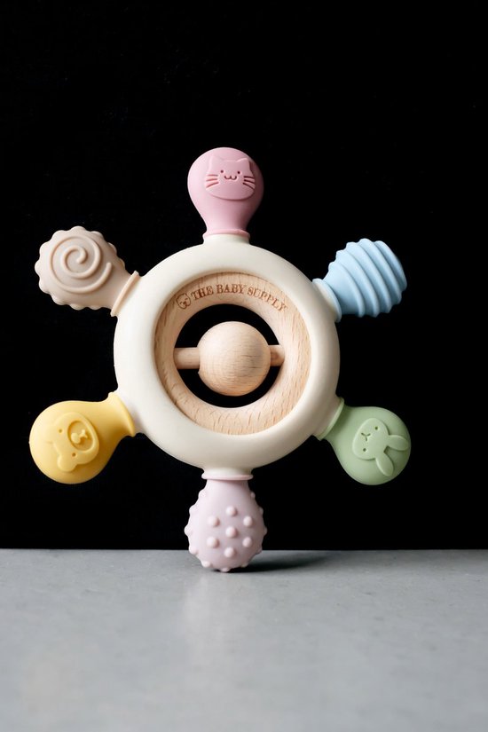 Een gebroken witte ring met vijf gekleurde uiteinden: katje (roze), konijn (lichtgroen), bal (lichtblauw), bloem (geel), bolletjes (lichtroze). Met houten middenstuk.