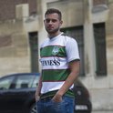 Man met wit met groen gestreepte voetbalshirt met 'Guinness' opdruk en clublogo.