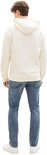 Man van achteren gezien in crème hoodie en blauwe jeans.