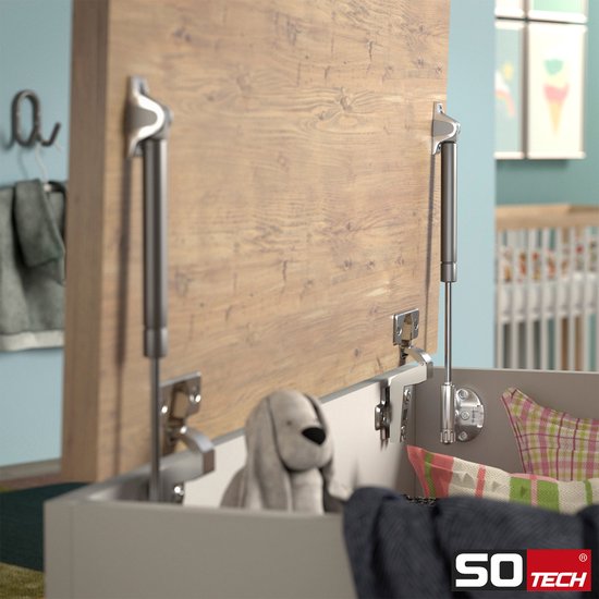 Een houten kist met twee geopende gasveren die het deksel omhoog houden. Een kinderkamer is op de achtergrond zichtbaar.