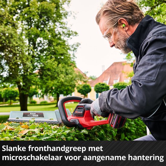 Een man met veiligheidsbril, handen op de slanke voorhandgreep van een rode Einhell heggenschaar.