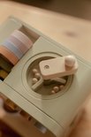 Detail van een houten speelgoed machine met pastelkleurige stapelringen en houten knoppen.
