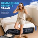 Vrouw staat naast een opgeblazen FLOAT luchtbed van 45 cm hoog, naast een open koffer.