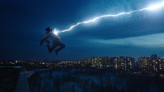 Een jongen in de lucht, geraakt door bliksem, met een stad bij nacht op de achtergrond.
