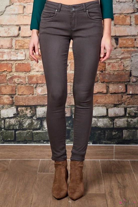 Modèle de face dans un pantalon push-up gris avec un haut vert foncé et des bottines marron.