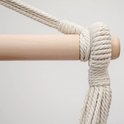 Een houten stok met aan weerszijden beige touwen, stevig vastgebonden.