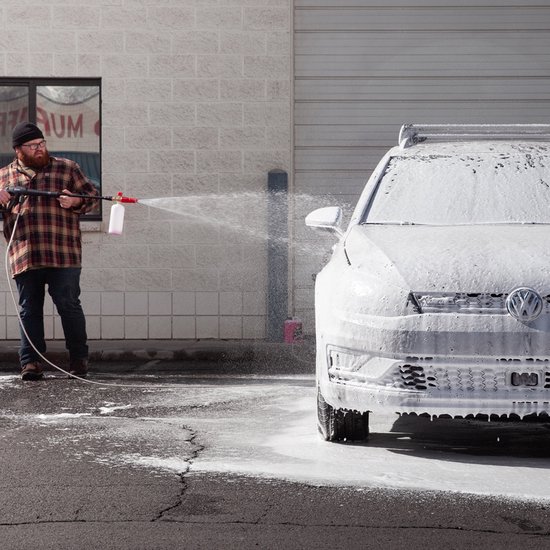 Man spuit schuim van Turtle Wax Snow Foam op een auto.