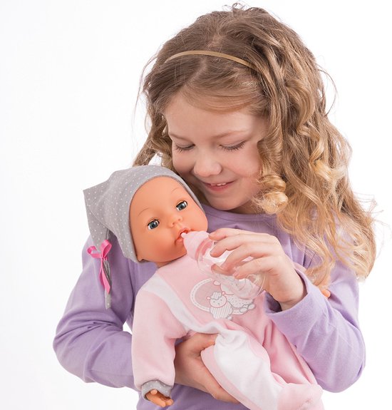 Meisje geeft een babypop met roze slaappakje en grijze muts een flesje.