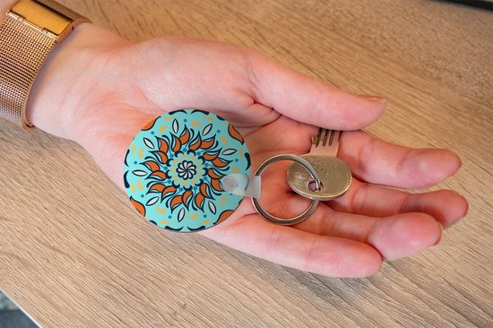 Porte-clés - motif sur fond bleu clair avec une fleur orange et des décorations - Plastique - Rond