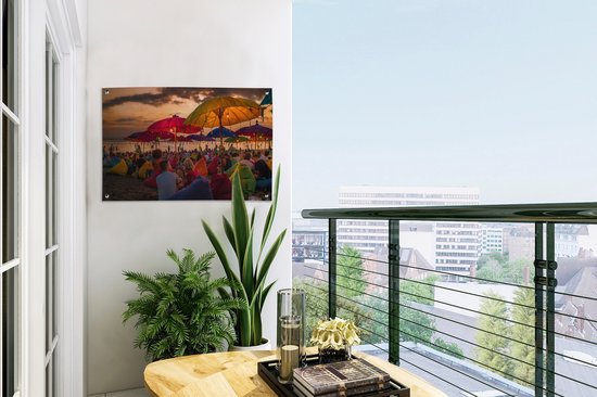 Tuinposter 60x40 cm - Tuindecoratie Toeristen genieten van de zonsondergang bij het strand van Denpasar in Bali, Indonesië - Poster voor in de tuin - Buiten decoratie - Schutting tuinschilderij - Tuindoek muurdecoratie - Wanddecoratie balkondoek