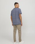 Man met gestreept blauw-wit T-shirt en beige chino broek, de achterkant zichtbaar.