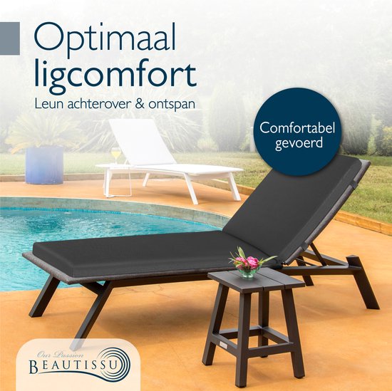 Een antraciet ligbed met comfortabel kussen in een tuin bij een zwembad.