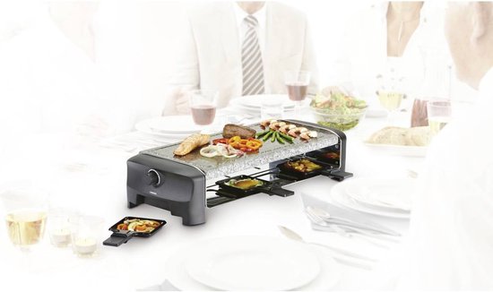 Raclette-grill met granieten plaat en aangeklede tafel, met gegrild vlees, groenten en brood.