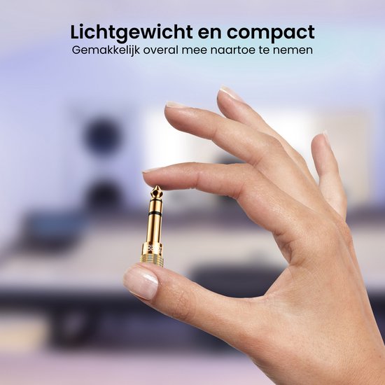 Hand houdt een kleine gouden audio jack adapter vast, die de compactheid benadrukt.