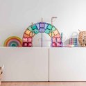 Gekleurde magnetische Connetix-tegels bouwen een regenboogbrug en een toren met transparante buizen, op witte kasten.