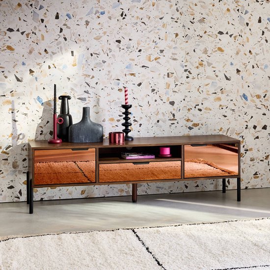 Houten tv-meubel met koperkleurige lades, donkergrijze en zwarte decoraties, en een witte plaid.