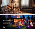 Man speelt gitaar in een woonkamer, met een hond en een zwarte luidspreker met led-verlichting. Mensen vieren feest in een tuin bij zonsondergang.