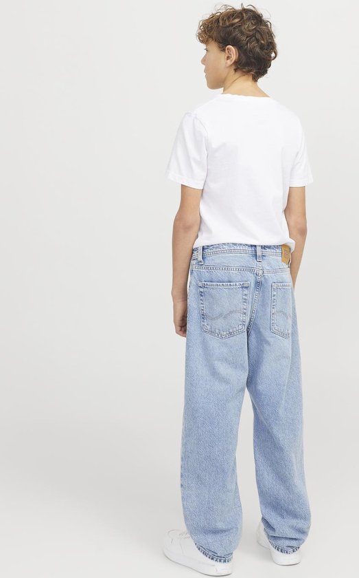 Jongen draagt een wijde, lichtblauwe spijkerbroek met een wit T-shirt, gezien van achteren.