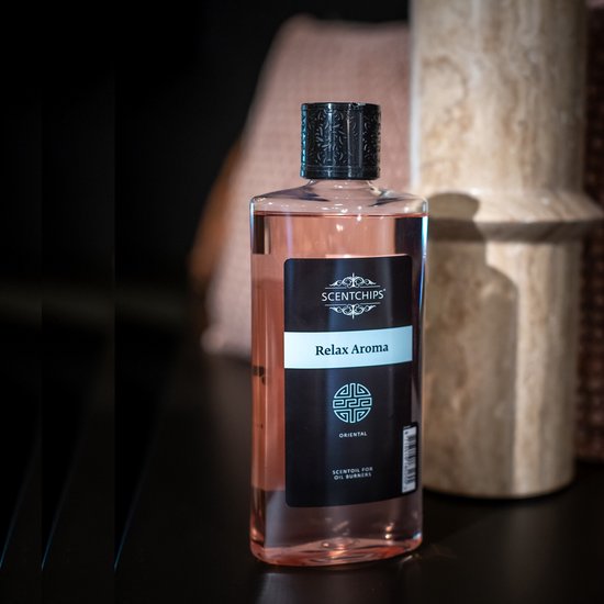 Een fles Scentchips 'Relax Aroma' met oranjegekleurde geurolie, gepresenteerd op een zwarte ondergrond.