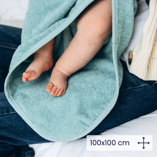 Détail des jambes et pieds d'un bébé dans une cape de bain bleue, "100x100 cm" est écrit en texte.
