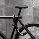 Zwart VINZ LOCKS kettingslot om de staander van een zwarte fiets.