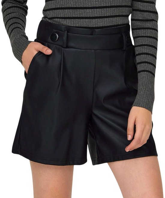 Close-up van een vrouw in zwarte faux leren shorts met strikdetail op de tailleband en zwarte knopen.