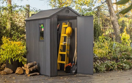 Grijze berging met open deuren, gele ladder, gele helm, schep en houtblokken.
