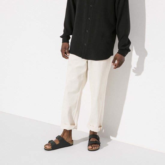 Man met zwarte Birkenstock Arizona slippers aan, met lichte broek.