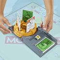 Kinderhanden bij Monopoly Uitbreiding Koop Alles spel met dobbelsteen en kaarten.