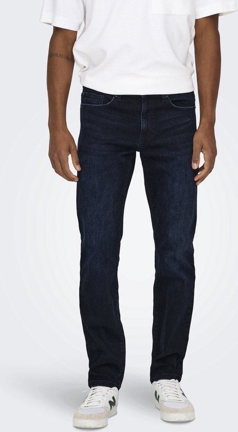 Man met donkerblauwe jeans, wit T-shirt en sneakers.