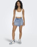 Model draagt een lichtblauwe denim skort met gekruiste overslag en knoopsluiting aan de voorzijde.