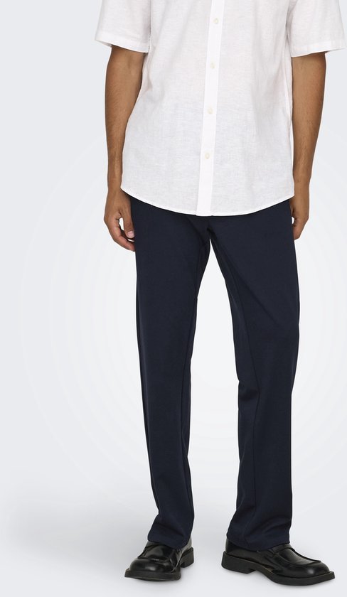 Man met donkere broek en wit hemd, staand.
