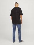Man van achteren gezien, draagt een zwarte T-shirt en blauwe jeans.