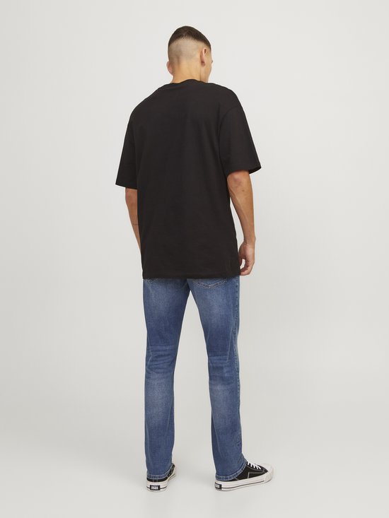 Man van achteren gezien, draagt een zwarte T-shirt en blauwe jeans.