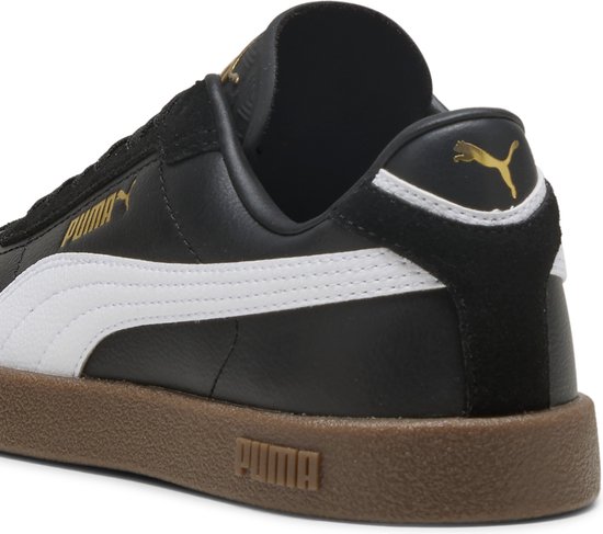 Detail van de hiel van een zwarte Puma sneaker met witte streep, gouden logo en bruine zool.