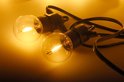 Twee warme, gloeiende transparante LED-lampjes van een lichtsnoer op een lichte achtergrond.